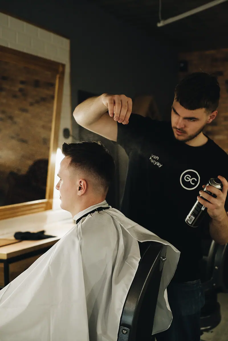 Barber styling client's hair in a contemporary shop, showcasing grooming and care.