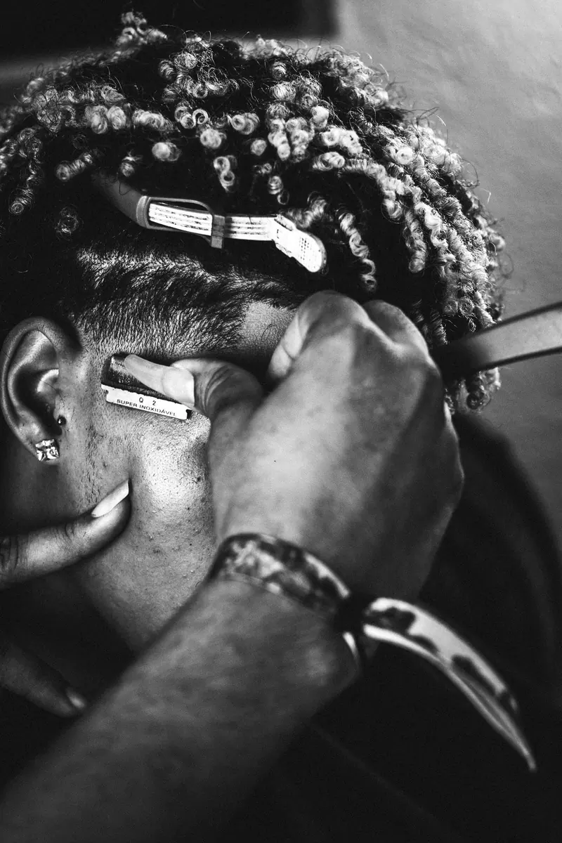 Intricate black and white shot of barber shaving hair with razor, highlighting professional craftsmanship.