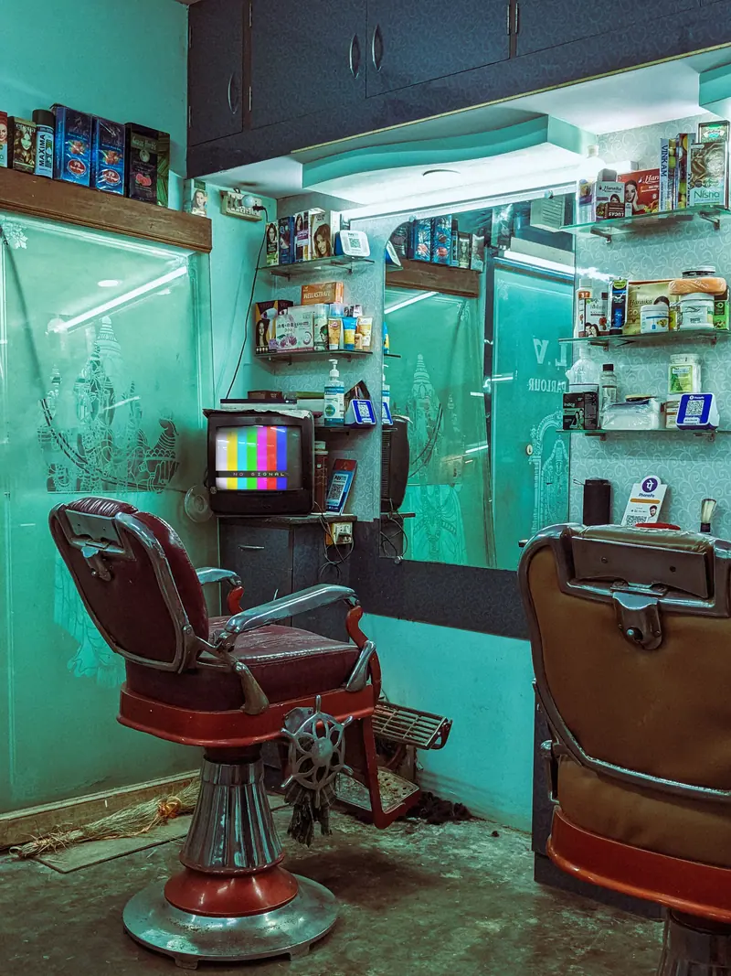 Red barber chair beside a green-tiled wall