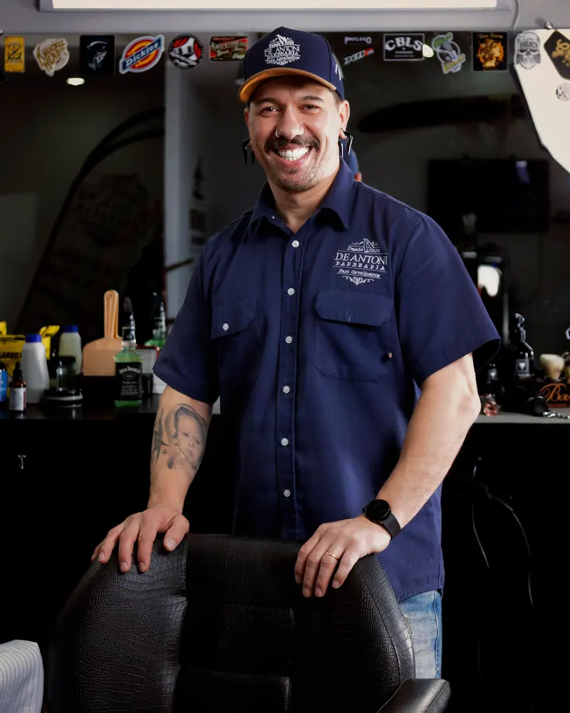 Smiling barber in a navy shirt in his shop