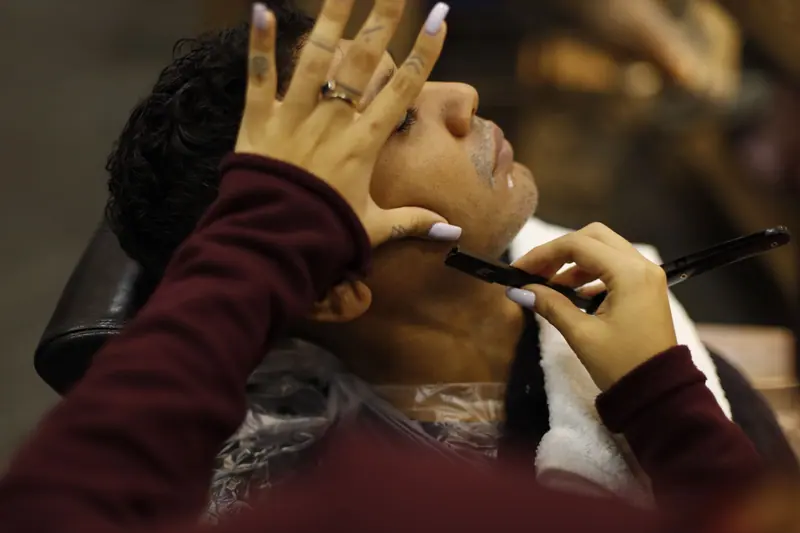 A man enjoys a professional shave at a barbershop, showcasing relaxation and grooming.