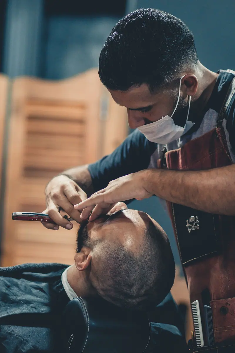 A skilled barber precisely shaving a client's head in a modern barbershop.