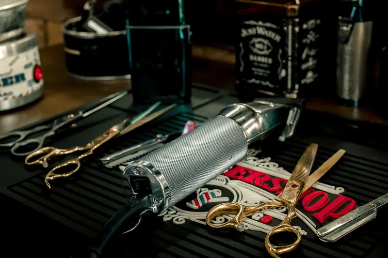 Close-up of barber tools including electric razor and scissors on a salon counter.