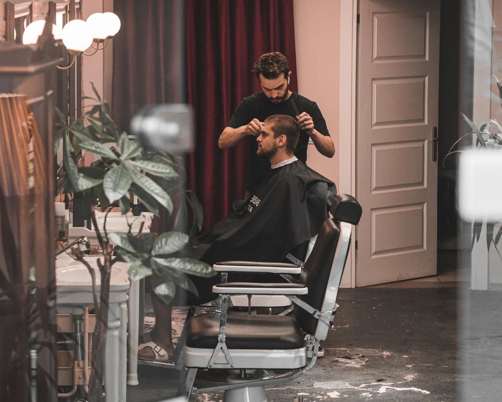 Barber styling a man's hair in a chic, modern salon interior, showcasing professional hairdressing skills.