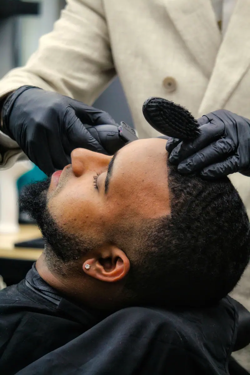 Barber in gloves shaping a client's beard