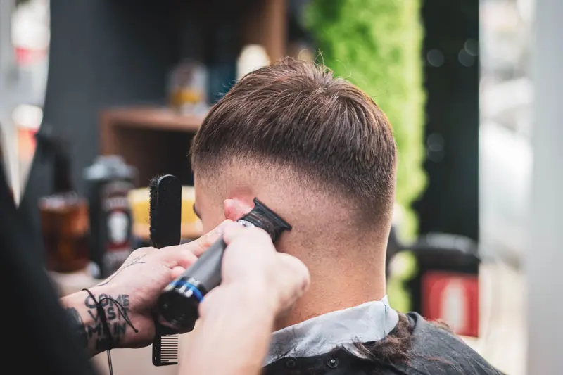 A barber skillfully trims a young man's hair in a modern salon setting, showcasing expertise and precision.