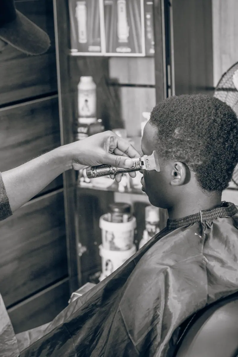 Black male client getting a haircut in a barbershop, highlighting professional grooming.