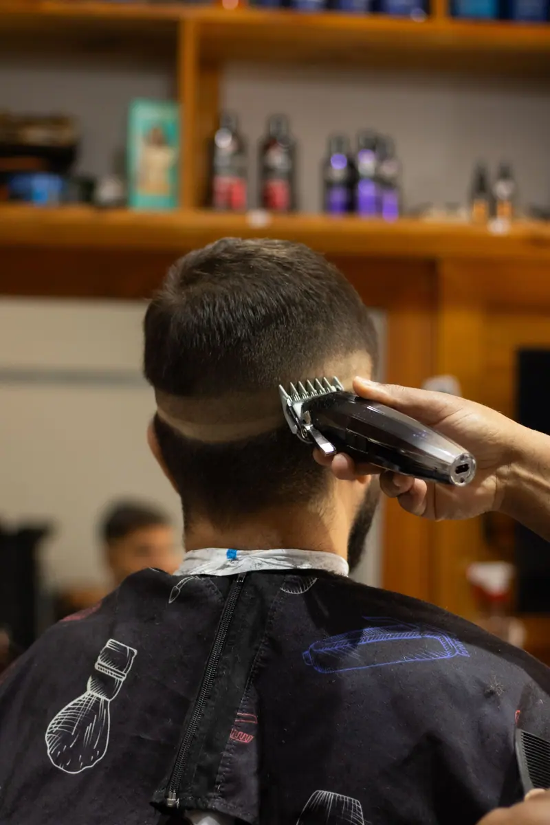 Barber using clippers to expertly trim a client's hair in a modern salon setting.