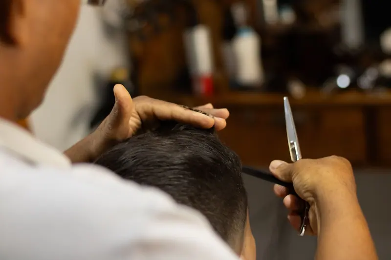 Focused shot of a barber cutting hair in a classic barbershop setting.