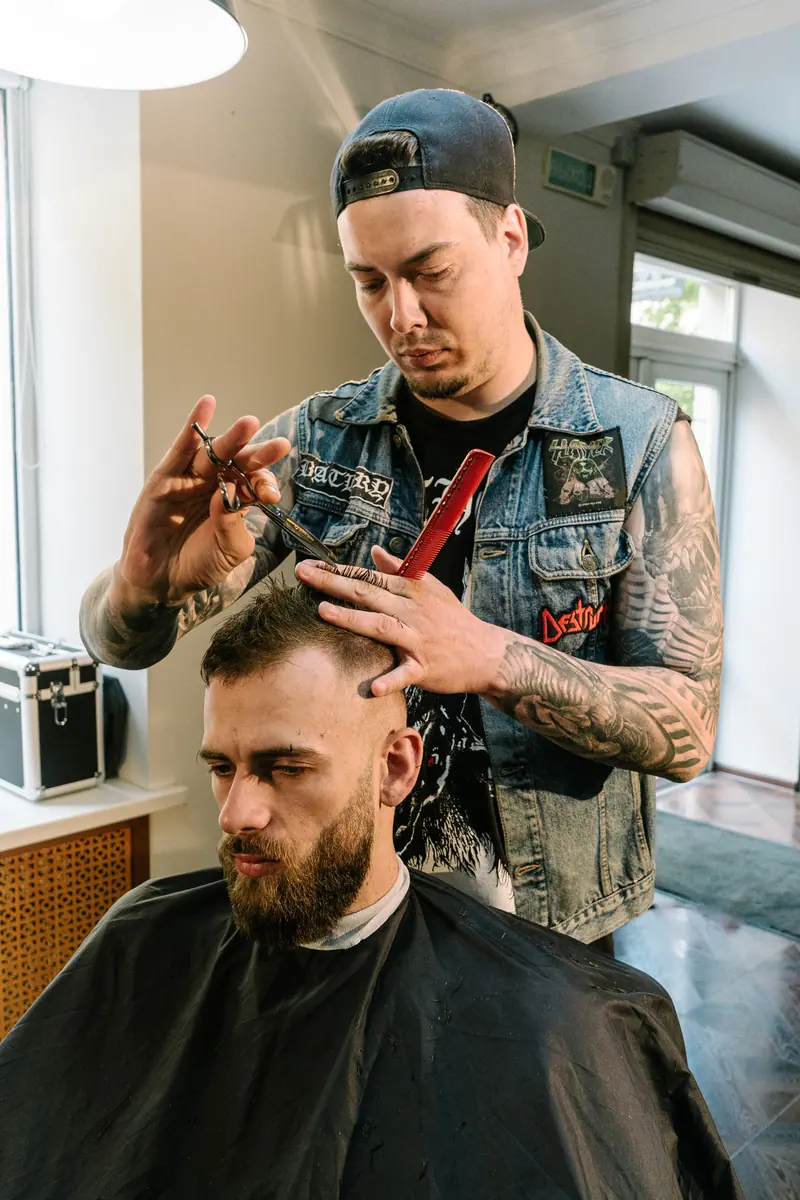 A skilled barber trims a man's hair in a trendy barbershop setting.