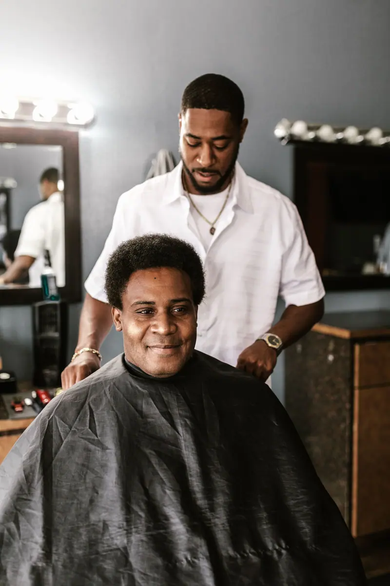 Barber in white shirt giving a haircut to smiling client in a modern and stylish barber shop.