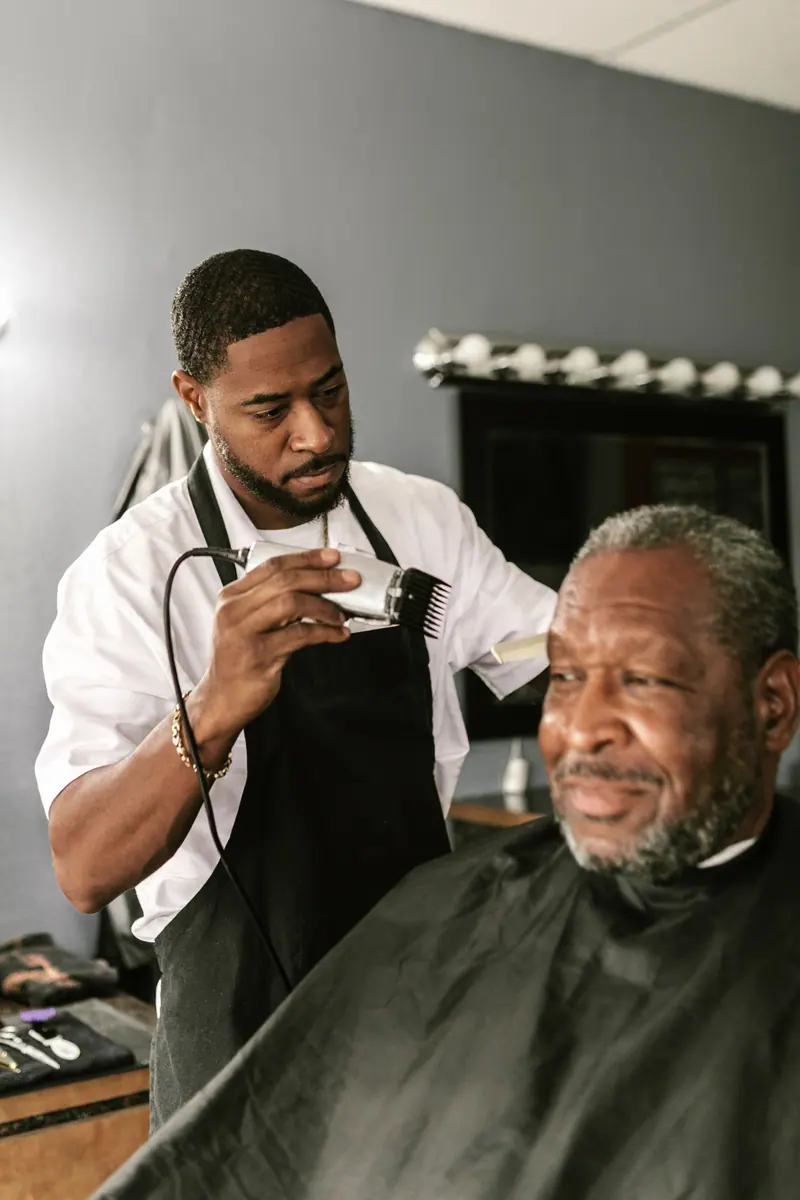 Barber skillfully cutting a customer's hair with clippers inside a modern salon.