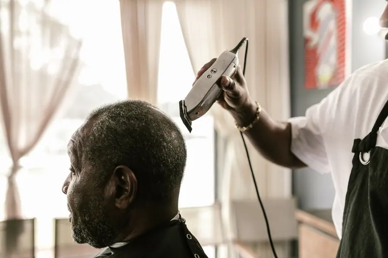 Barber blow-drying a client by the window