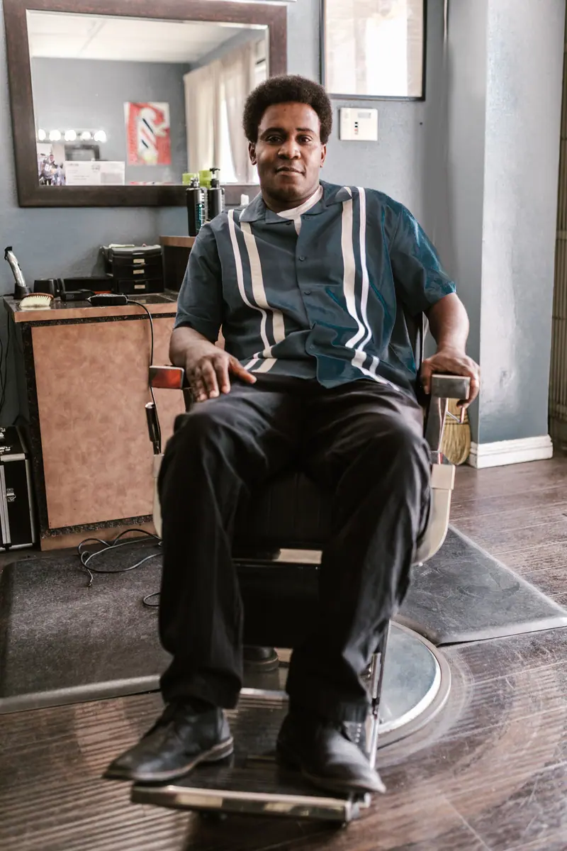 Man sitting comfortably in a barber chair inside a cozy barber shop.