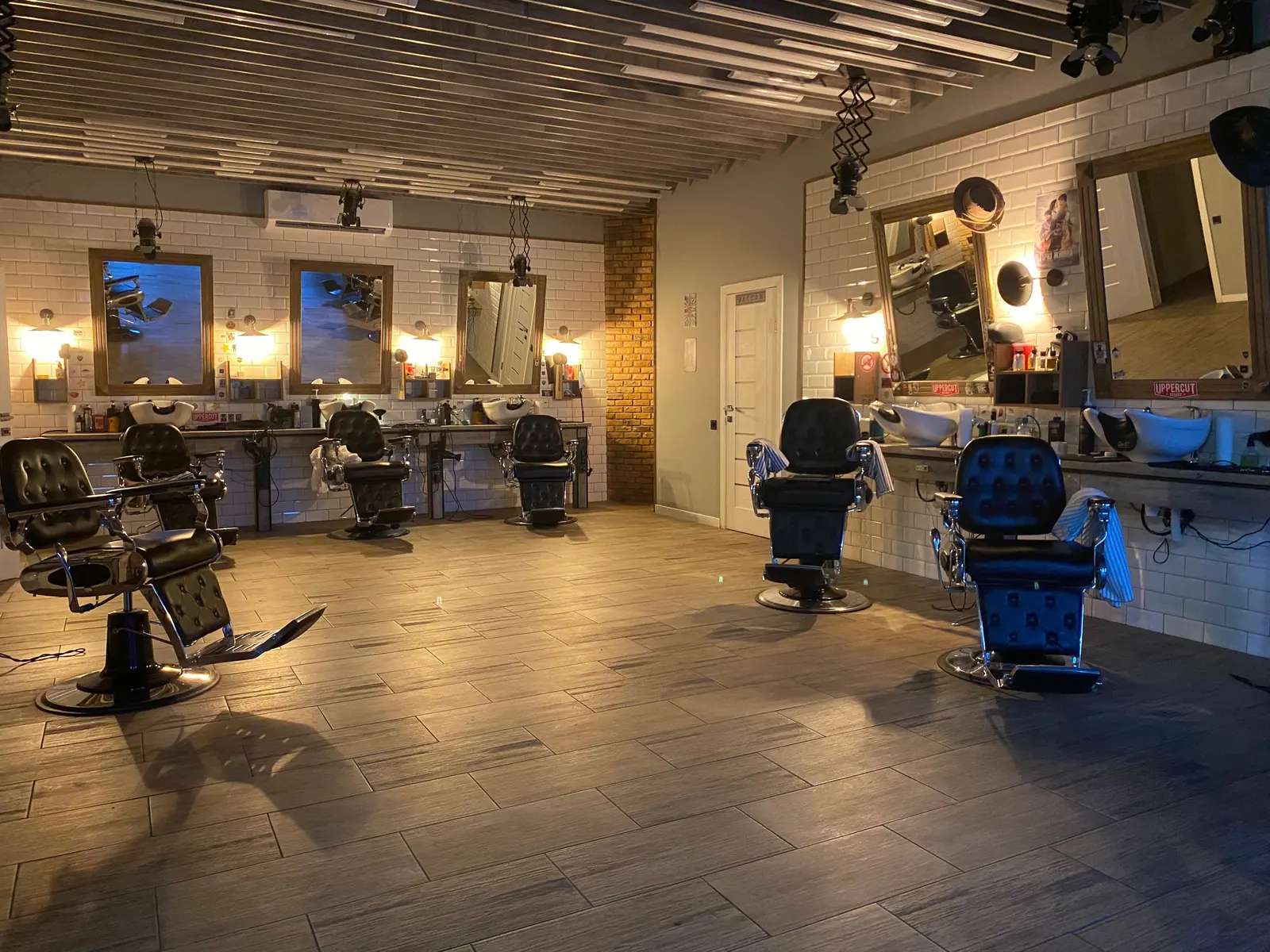 Warmly lit barber lounge with leather chairs, brass fixtures and Edison bulbs at dusk