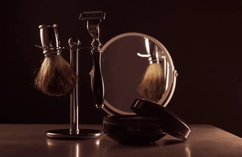 Stylish shaving set featuring a brush, razor, and mirror on a table, ideal for men's grooming.
