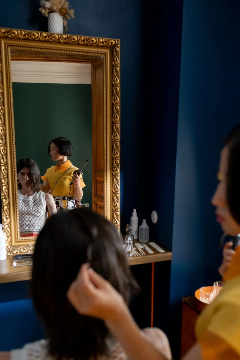 Stylist working before a gilded mirror against cobalt walls