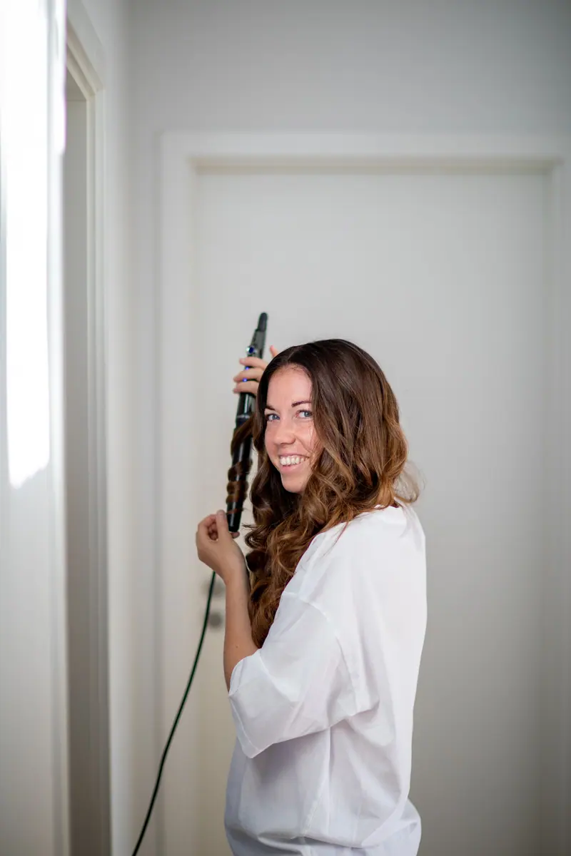 Curling long dark hair by the window