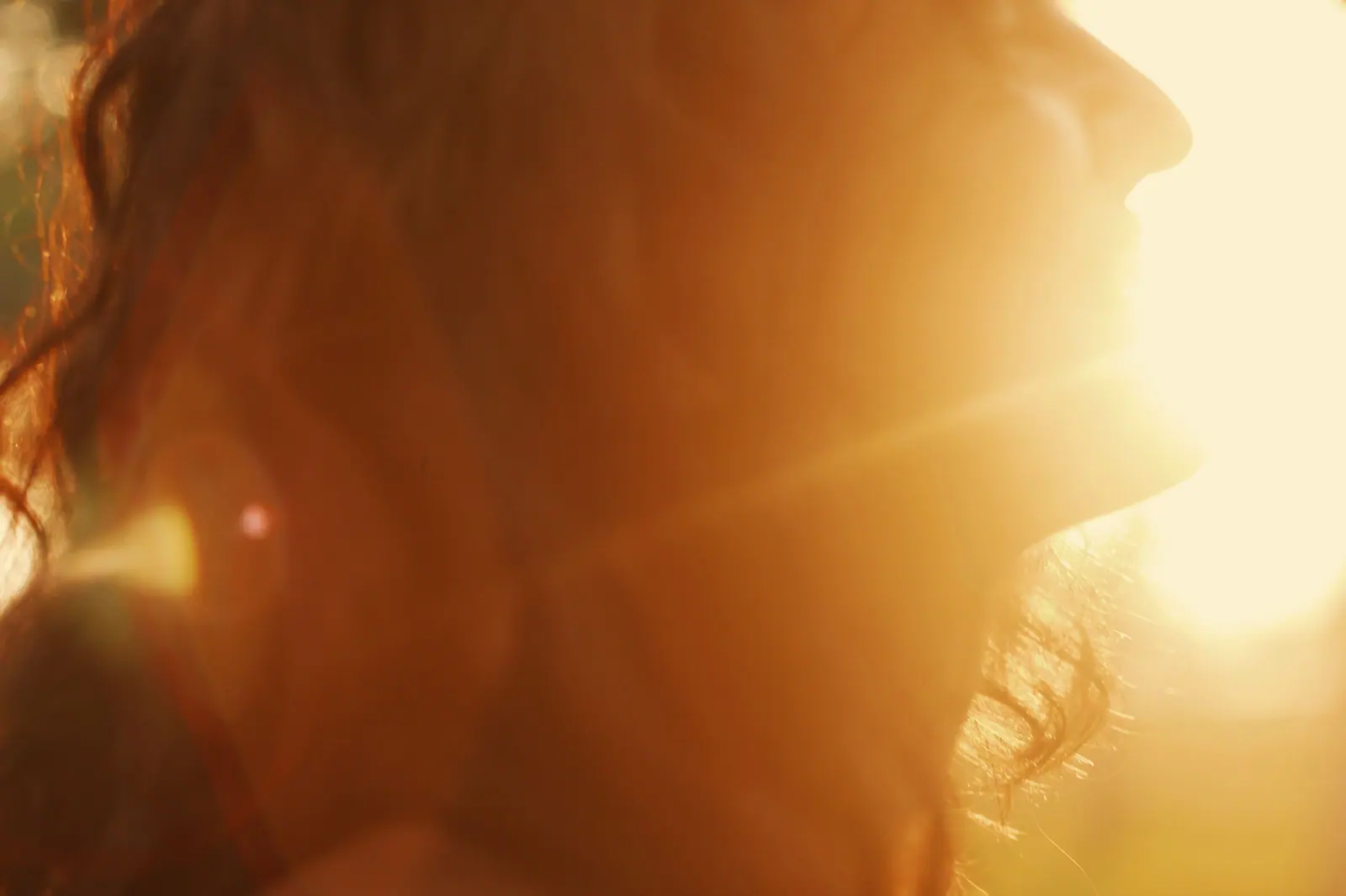 Woman with long auburn hair glowing in warm, golden sunset light