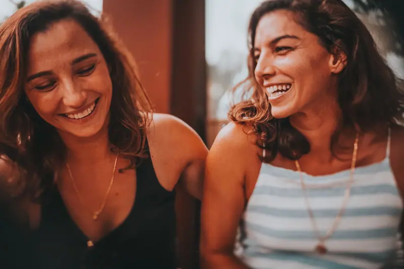Two friends laughing in warm light