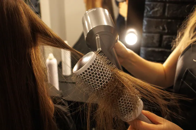 Round-brush blowout in a warm, low-lit salon