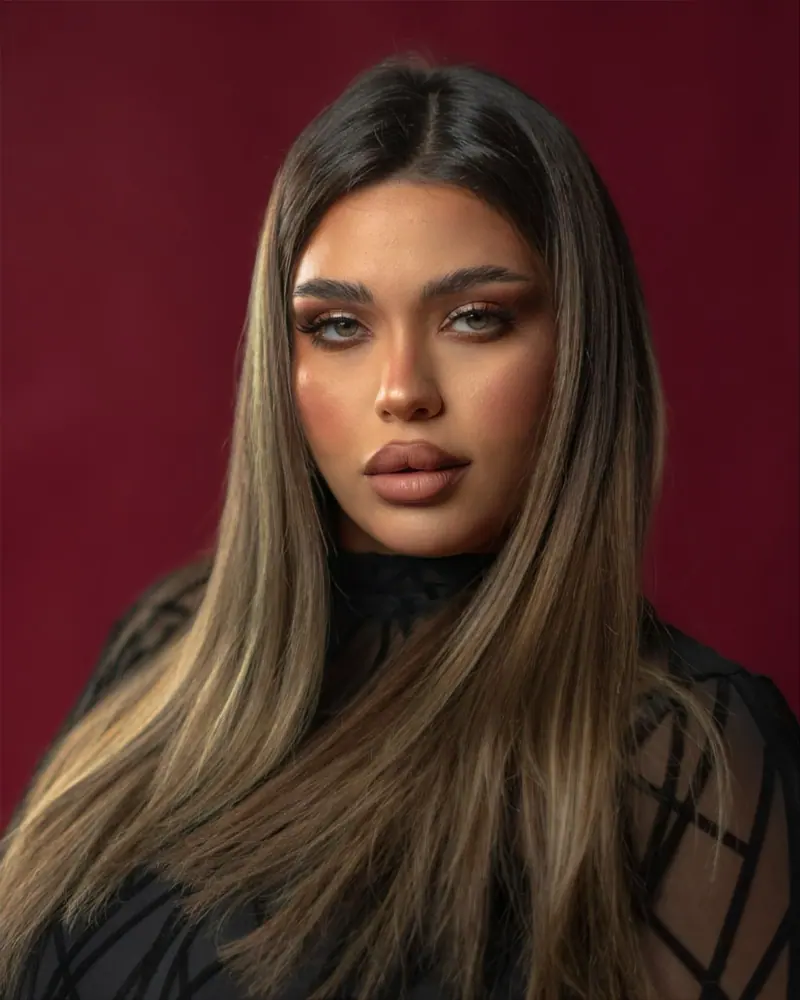 Woman with sleek, glossy lengths against a deep red wall