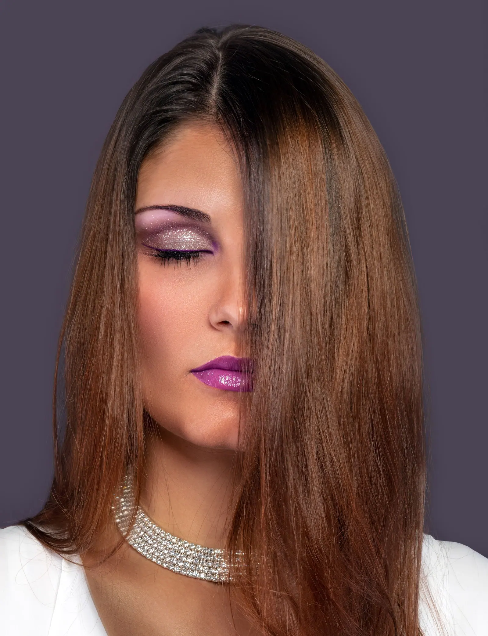 Woman with sleek, glossy copper-brown hair and violet makeup in a studio portrait
