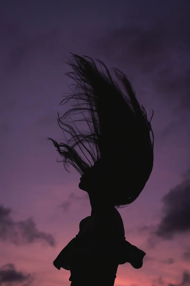 Hair flip silhouetted against a purple dusk