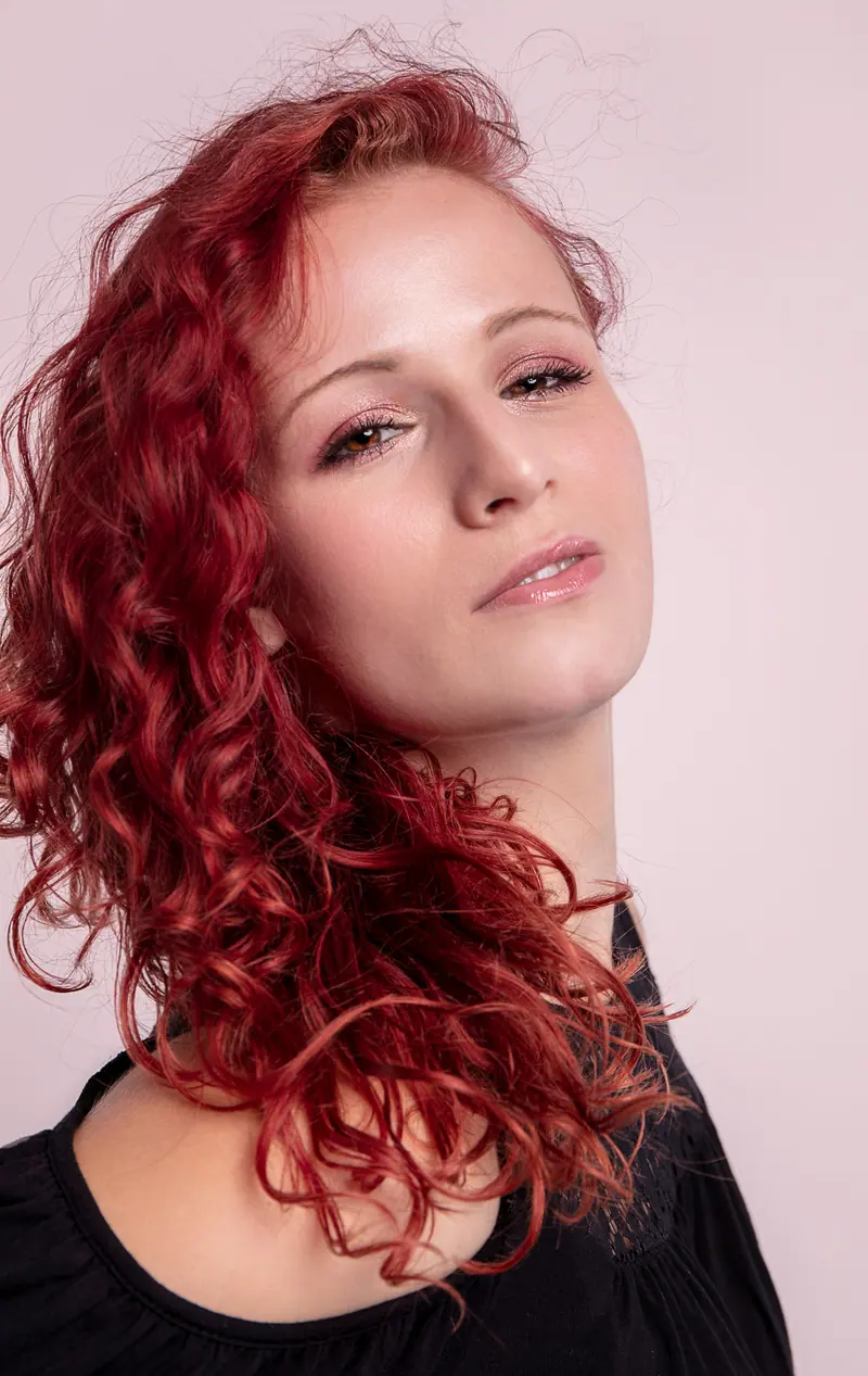 Red curls against a soft backdrop