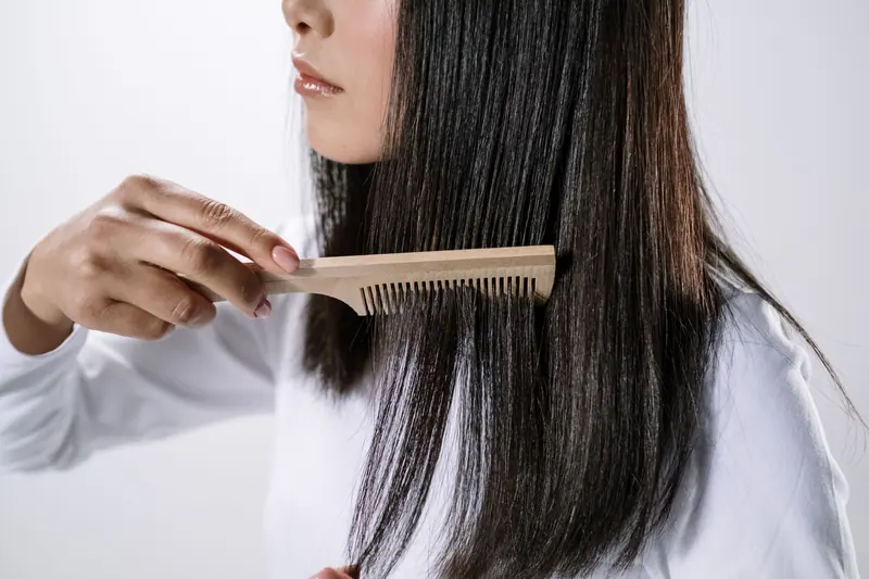 Combing through long dark hair with a wooden comb