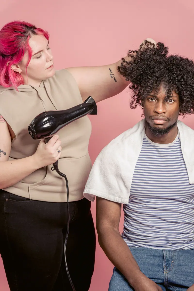Stylist with pink hair drying a client's curls