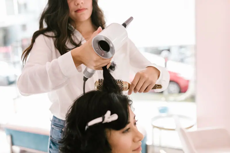 Stylist finishing a blowout with a round brush
