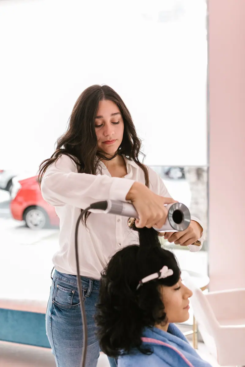 Stylist blow-drying a client in a bright salon