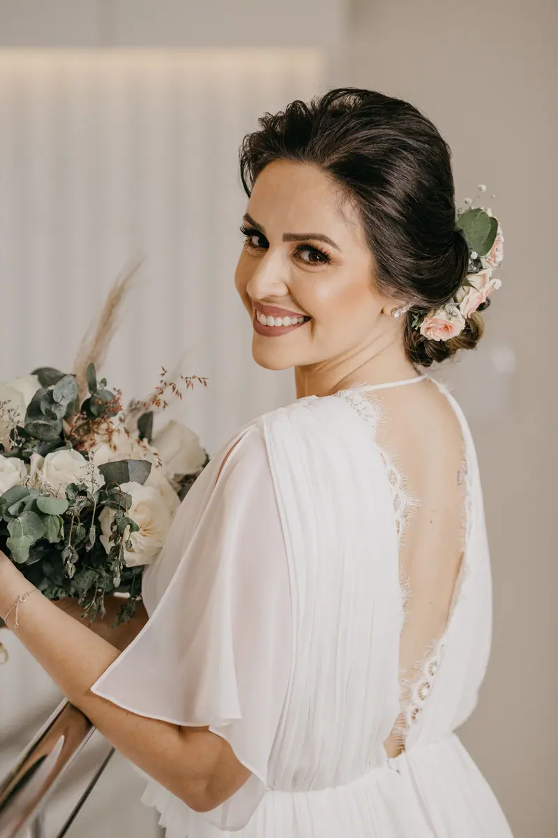 Smiling bride in white dress holding floral bouquet; perfect wedding portrait.