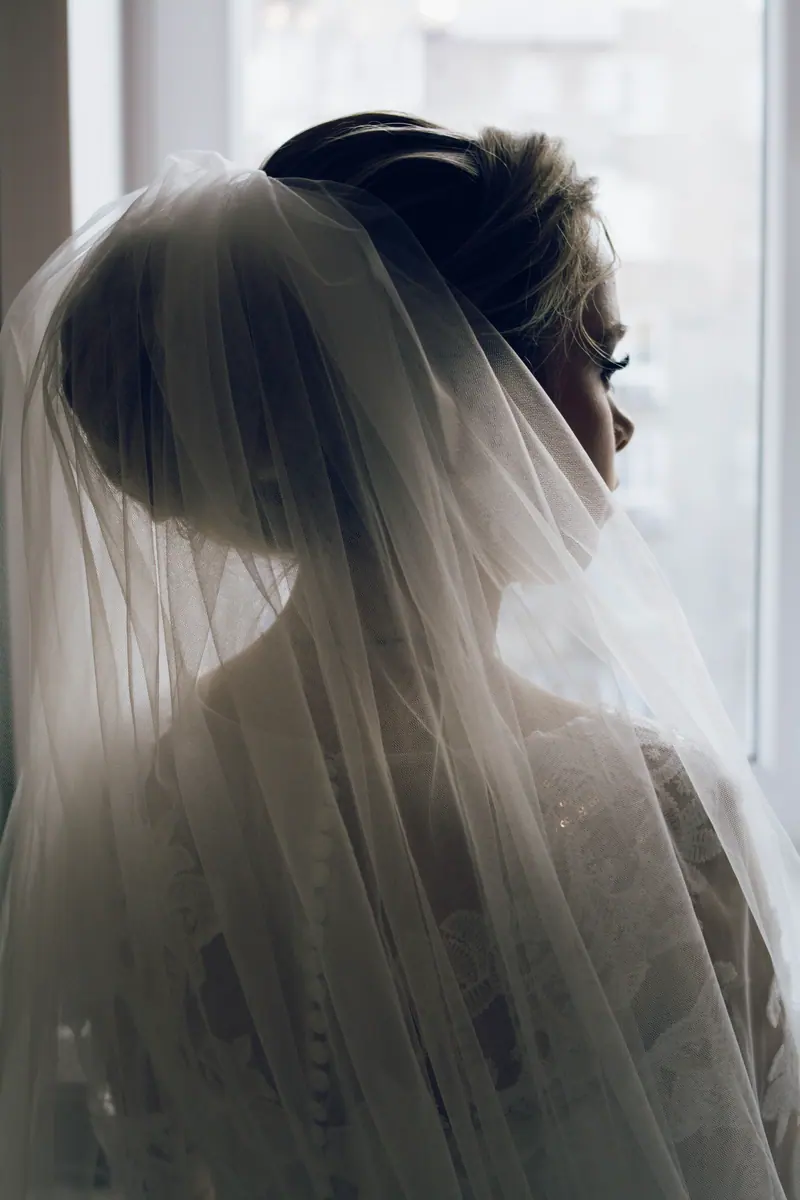 A serene silhouette of a bride in an elegant veil, capturing a moment of reflection.