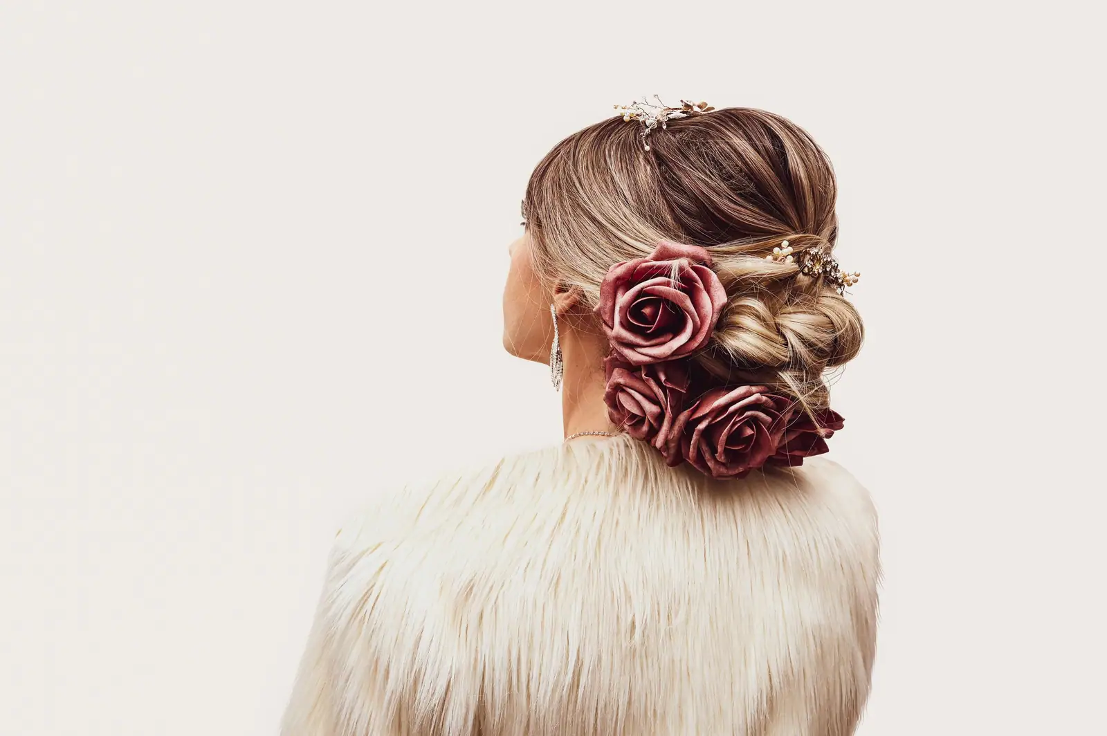 A sculpted bridal low bun pinned with deep red roses
