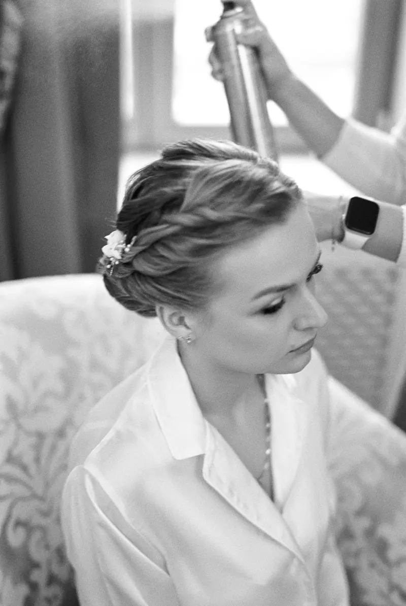 Young woman getting an elegant hairstyle with hairspray application, showcasing a timeless look.