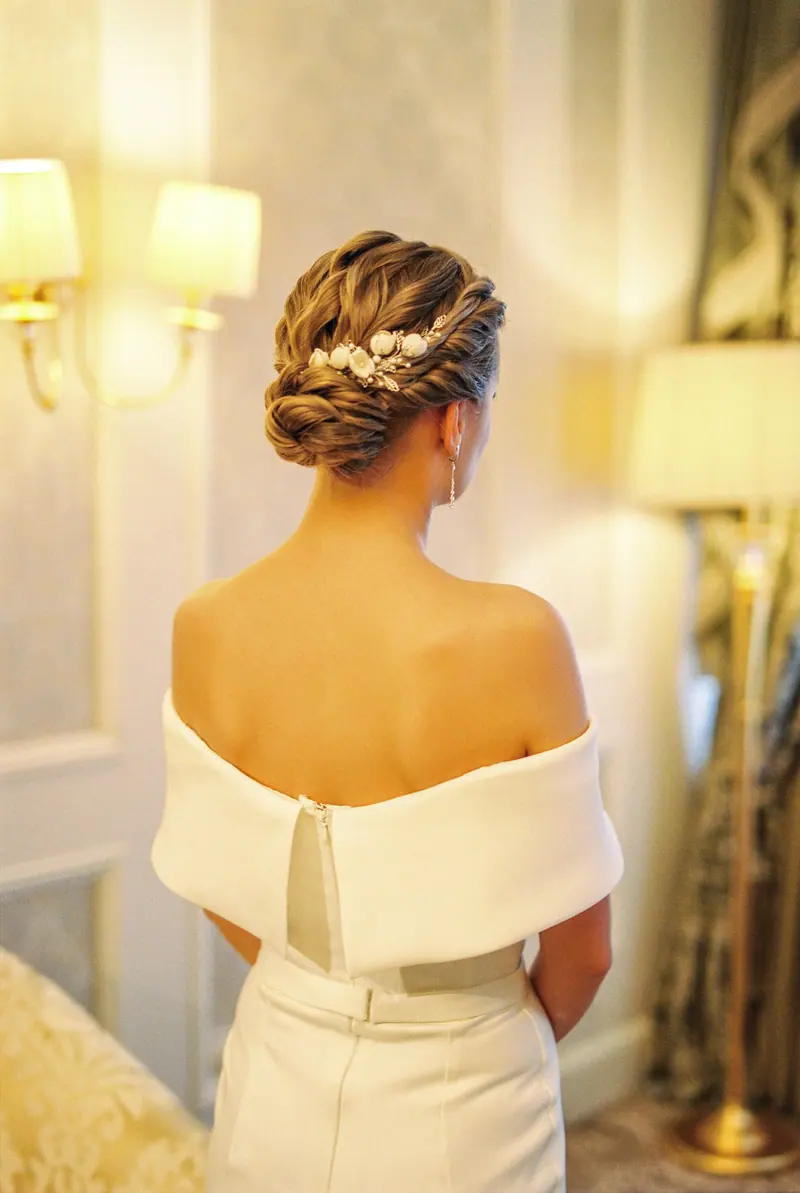 Rear view of a bride with an elegant updo wearing a wedding dress indoors.