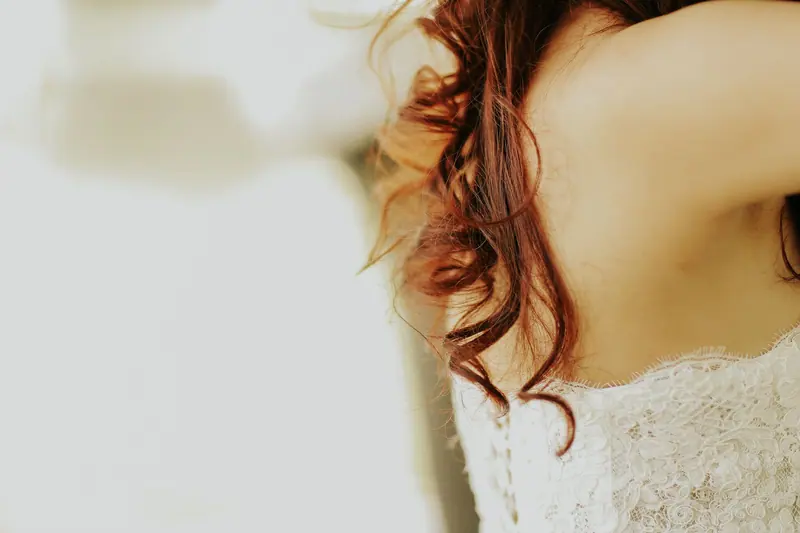 Close-up of a bride's delicate lace dress and elegant curly hairstyle, capturing wedding elegance.
