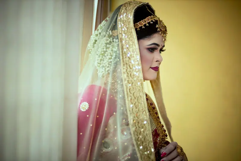 Stunning bride in traditional embroidered attire with golden jewelry and veil.
