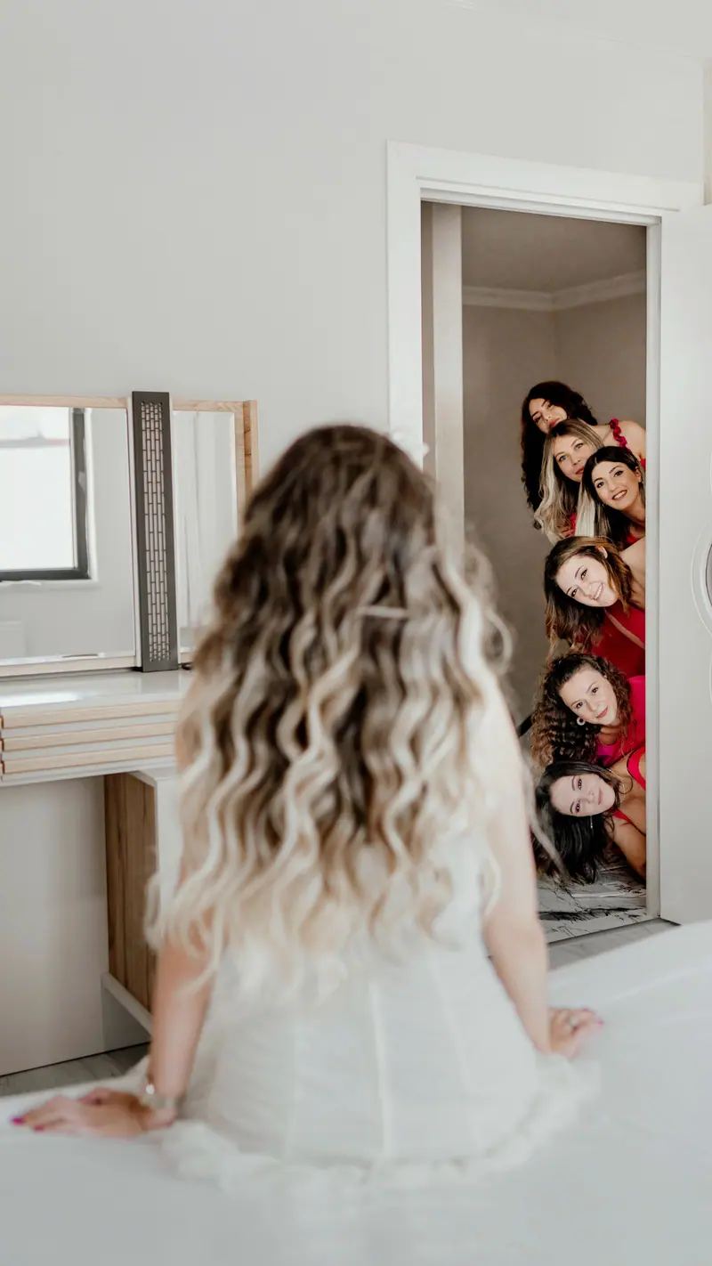 Joyful bridesmaids and bride having a playful moment during wedding preparations indoors.
