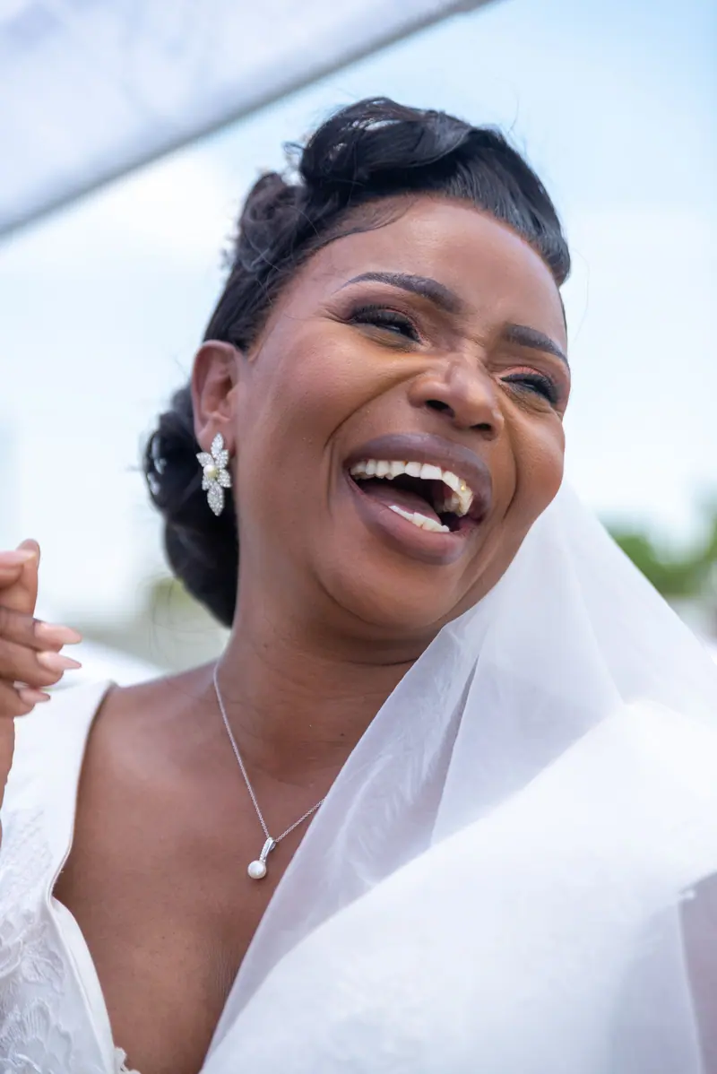 A delighted bride laughing joyfully, captured in an outdoor wedding setting.