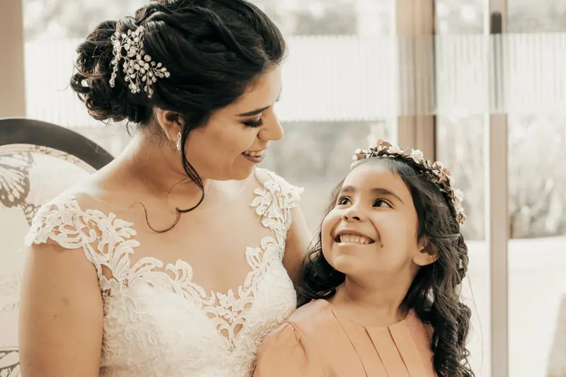 A mother and her daughter share a joyful moment together, smiling warmly during a wedding celebration.