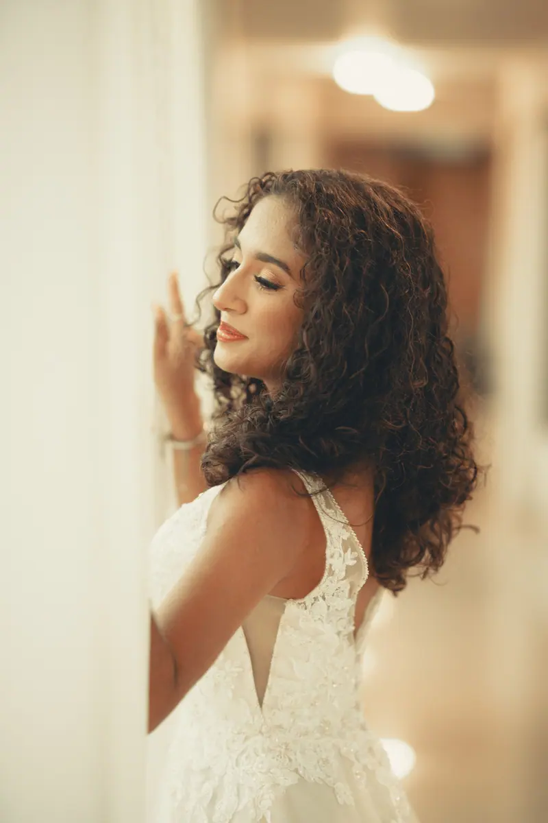 Beautiful bride in a lace gown posing indoors, exuding elegance and poise.