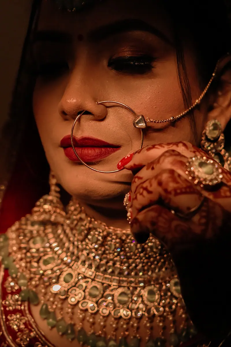 Close-up portrait of a bride wearing traditional Indian jewelry and henna artwork.