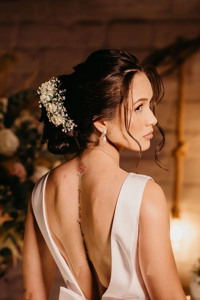A stunning bride in a low-back dress, beautifully styled for an indoor wedding.