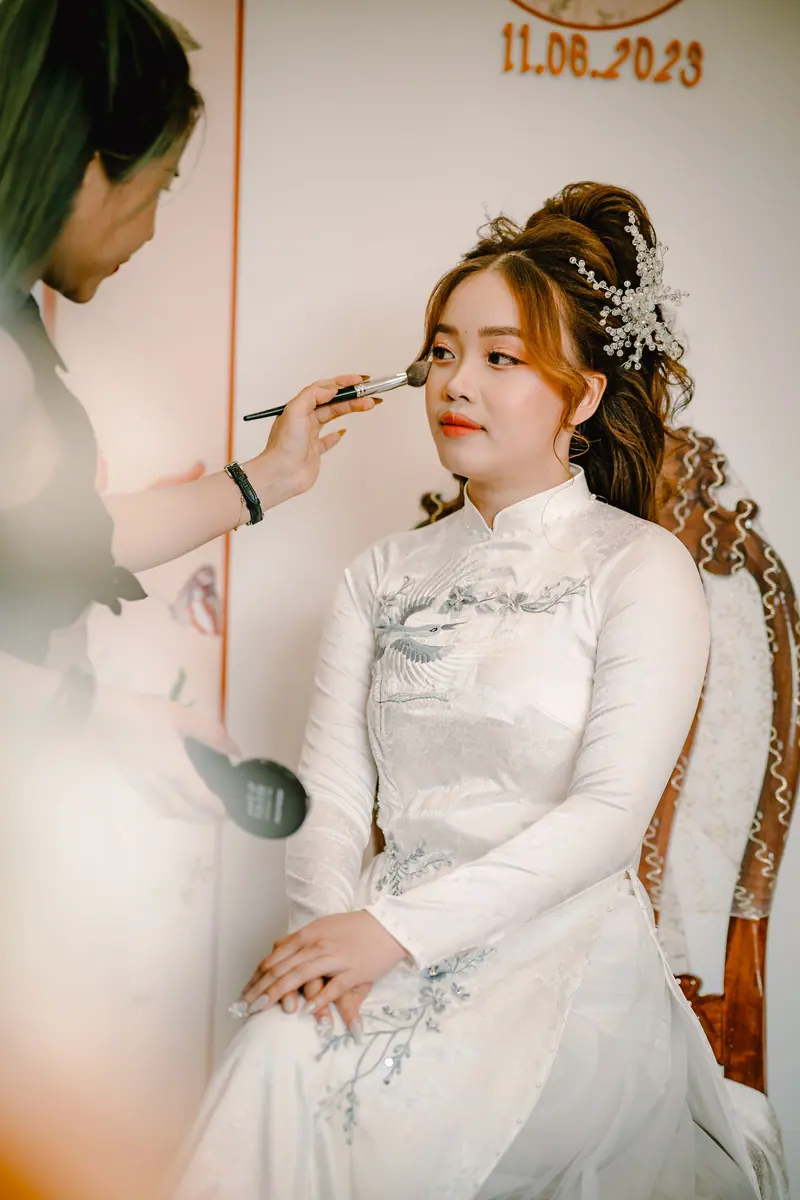 A bride getting her makeup done in preparation for her wedding day in an elegant setting.