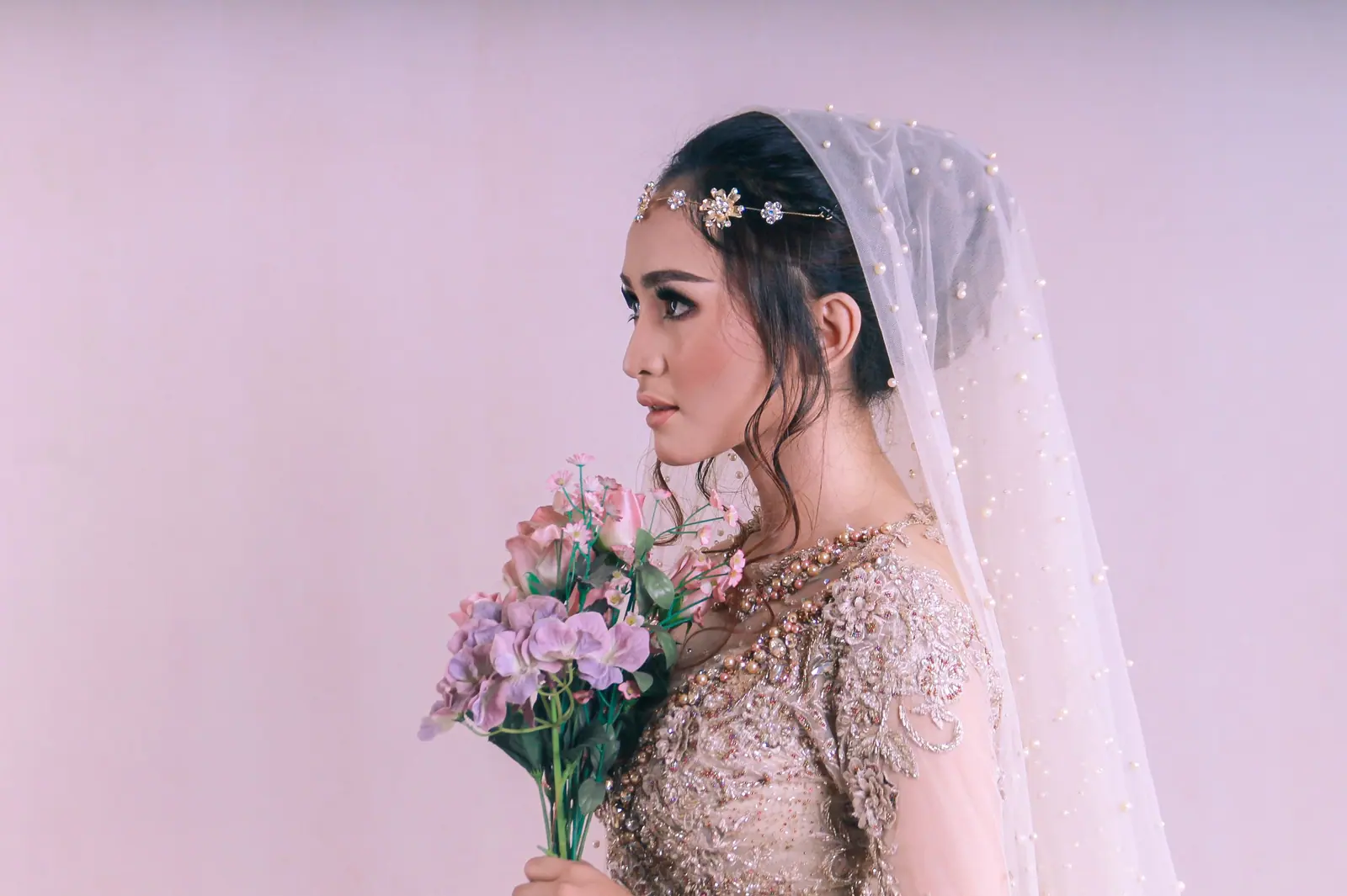 Elegant bridal portrait with veil and bouquet in a studio setting. Perfect for wedding and fashion collections.