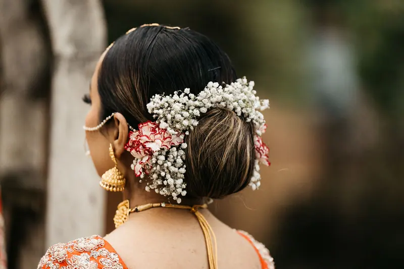 Back view of a woman with a floral hair wreath and elegant jewelry.