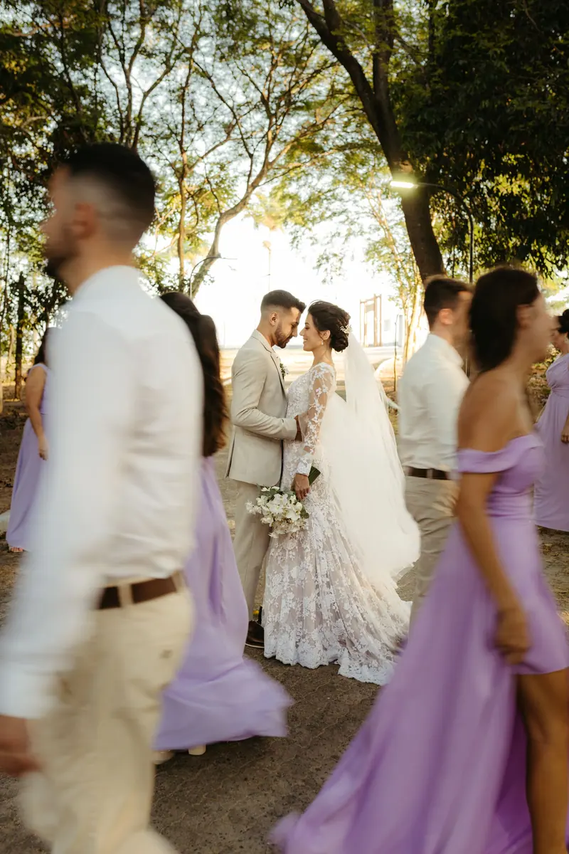 Bride and groom surrounded by bridesmaids and groomsmen in lavender dresses, celebrating their outdoor wedding.